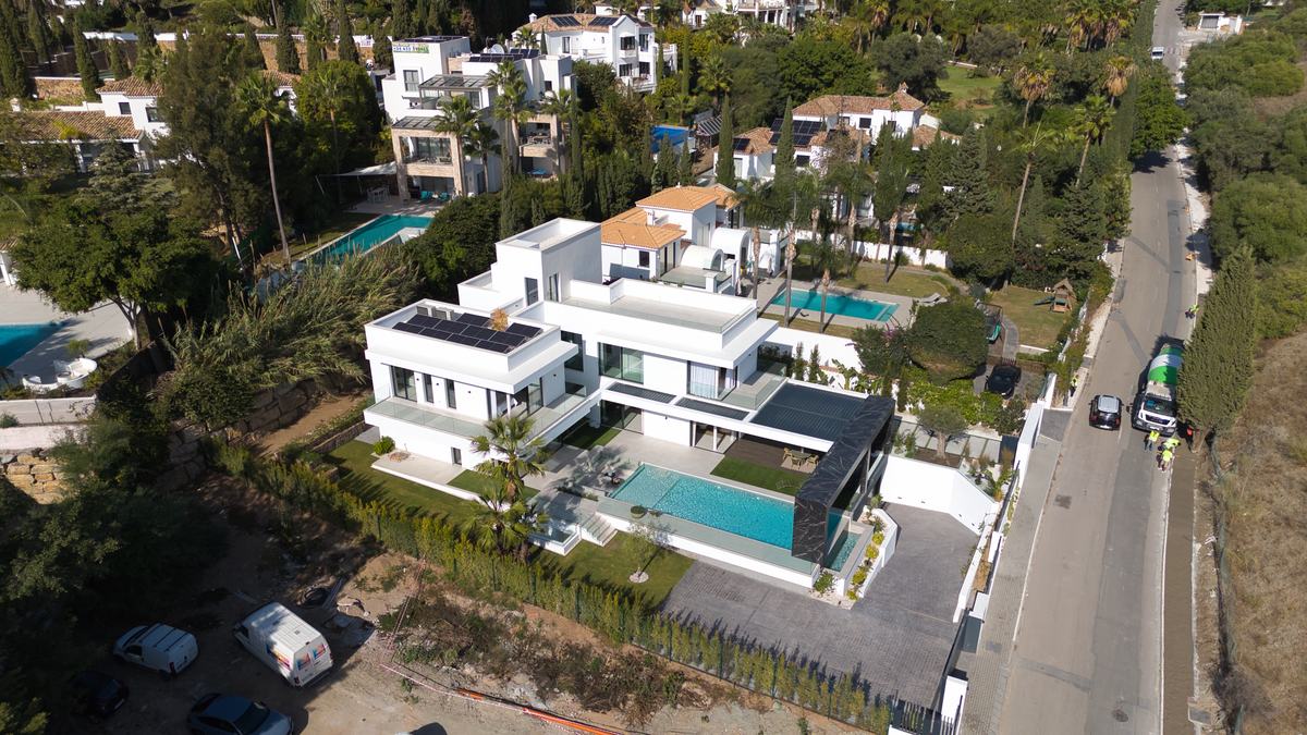 Aerial view of a newly built white villa with pool
