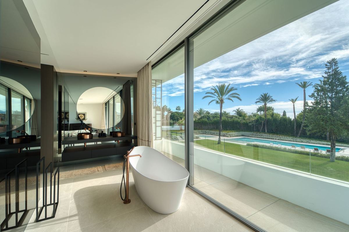 Bathroom with freestanding bath looking out over the pool