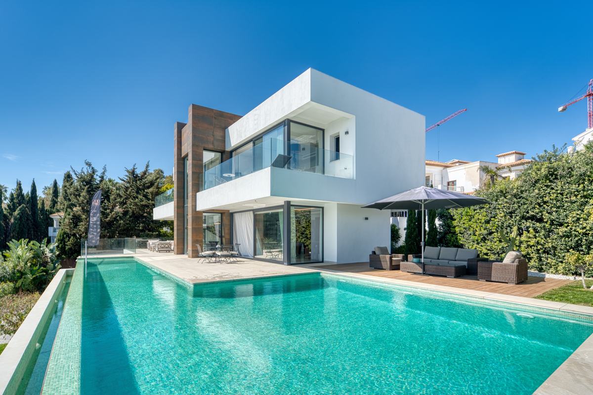 White villa with corten steel detail beside a long pool